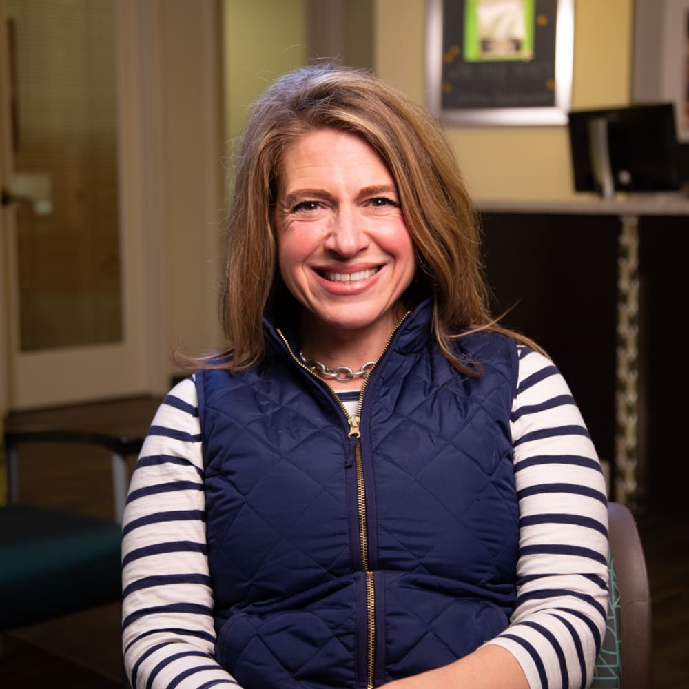 A woman sitting in the Nalchajian Orthodontics reception area smiles at the camera.