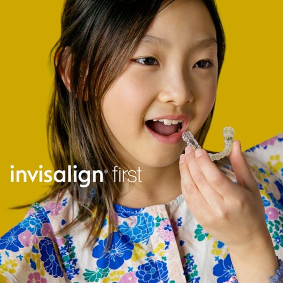 A young girl with bright white teeth smiles at the camera.
