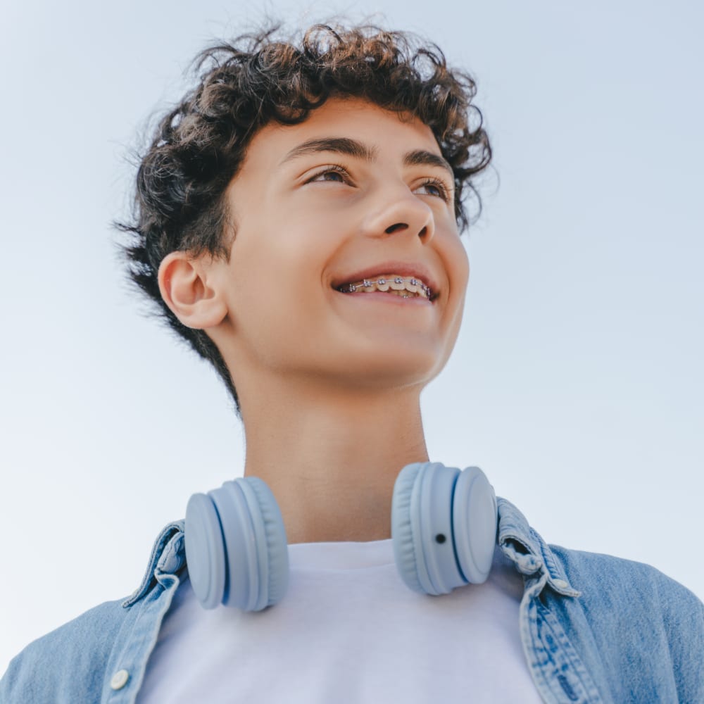 A teenage boy smiles, showing off his braces.