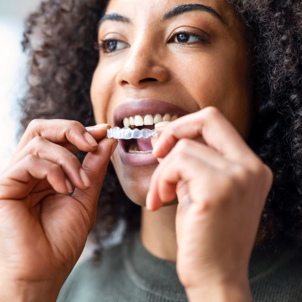 A woman puts on her Invisalign clear aligners.