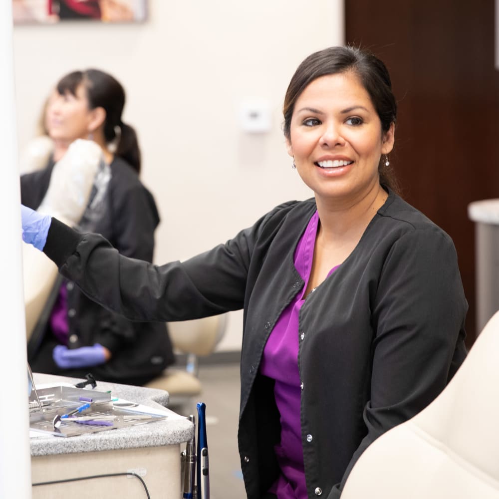 A team member at Nalchajian Orthodontics is smiling, with one hand on her computer.