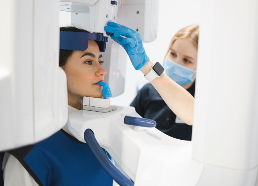 A patient sits with their face in a 3D iCAT Scan machine.