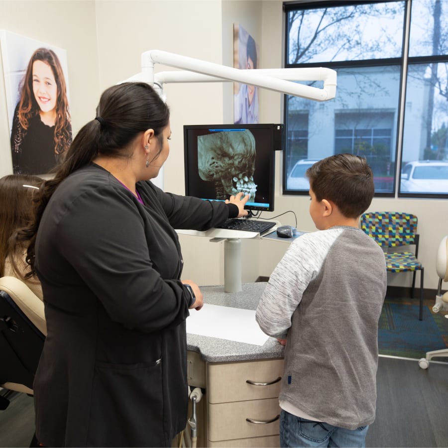 A team member at Nalchajian Orthodontics shows a young patient his X-rays.